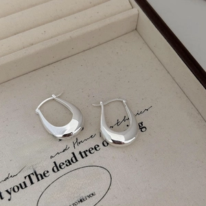 Detail of polished S925 sterling silver U-shaped earrings on beige velvet jewelry box