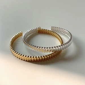 Detail view of gold and silver irregular corrugated texture open cuff bracelets
