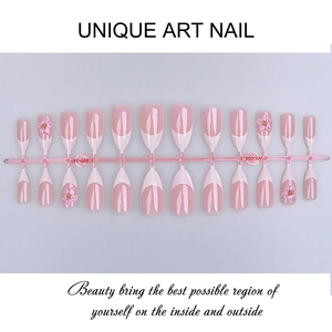 Close-up of pink French press-on nails with 3D floral accents and glossy almond shape