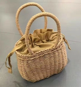 Detail of hand-woven straw basket bag with khaki drawstring lining and sturdy dual handles