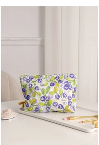 Detalle de neceser floral con estampado de arándanos y etiqueta de marca blanca