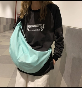 Close-up of light blue nylon crescent bag worn by a model in a casual street style look