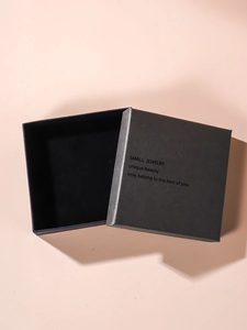 Macro view of a minimalist black square jewelry gift box with textured paper lid