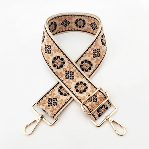 Detail of vintage floral embroidery on wide adjustable bag strap with gold metal hooks