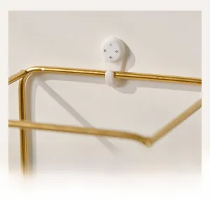 Detail of Nordic gold metal wall shelf with white non-marking hooks for easy installation