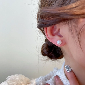 Close-up of minimalist round pearl stud earring worn by model for elegant style