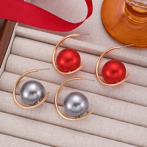 Macro view of C-shaped metal earrings with red and silver grey pearls on silk