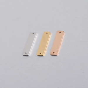 Detailed view of rectangular stainless steel tags in silver, gold, and rose gold finishes