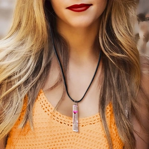 Collana con ciondolo rettangolare in resina e fiore secco rosa indossata su top arancione