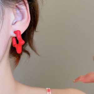 Macro view of matte red acrylic star earrings worn by a model in a modern style