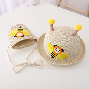 Detailed view of woven straw sun hat and matching bag with cute 3D bee decorations