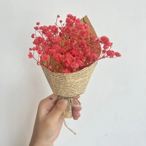 Close-up of mini red dried flowers bouquet wrapped in vintage kraft paper with twine
