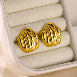 Detail of golden stainless steel stud earrings with spiral petal texture in a jewelry box