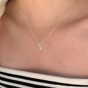 Close-up of minimalist S925 silver necklace with a light blue crystal pendant on model