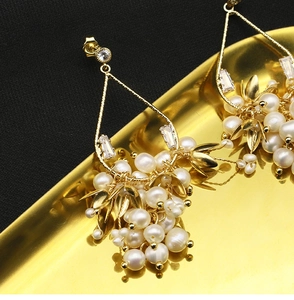 Vue macro de boucles d'oreilles en perles naturelles avec feuille dorée sur plateau d'or