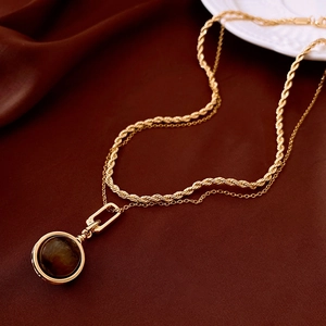 Detail of a vintage double-layer golden necklace with tiger eye stone pendant on silk