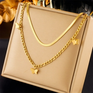 Close-up of gold layered necklace with butterfly pendants on a beige jewelry box