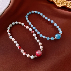 Detail view of Shoushan stone beaded bracelets with blue and red textures on silk fabric