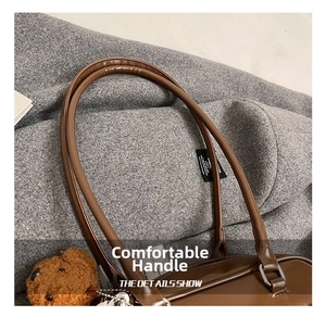 Close-up of leather handle and bear charm on dark brown vintage shoulder bag