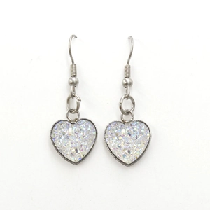 Close-up of heart-shaped earrings with shimmering white finish and silver-tone fish hooks