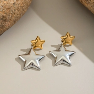 Macro detail of two-tone gold and silver star earrings on minimalist stone surface