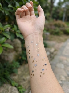 Detail of waterproof gold and silver star tattoo stickers with metallic glitter on skin