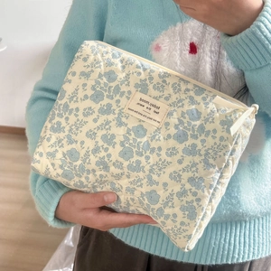 Close-up of quilted floral cosmetic bag featuring blue flower patterns and metal zipper