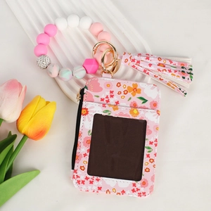 Close-up of pink floral card holder with silicone bead bracelet and decorative tassel
