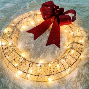 Detail of metal Christmas wreath with LED warm lights, red bow and glitter berries