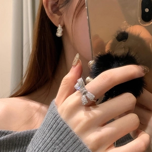 Elegant silver bow zircon open ring with white pearl earrings on model in warm setting