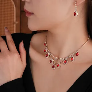 Elegant gold jewelry set with red teardrop gems and tassels worn by a model