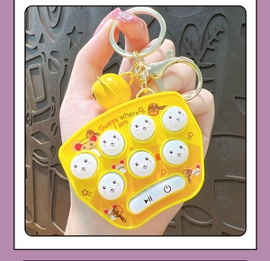 Close-up of yellow electronic Whack-a-Mole keychain game with buttons and bell accessory