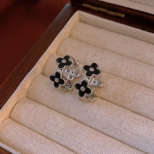 Detailed macro view of silver clover hoop earrings with black petals and small diamonds