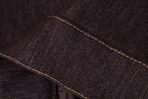 Vue macro du tissu denim indigo foncé avec des coutures contrastées orange vif