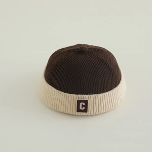 Close-up of two-tone knit Miki hat featuring a letter C patch and soft ribbed texture