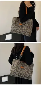 Detail of leopard print tote bag with brown faux leather handles and metal chain accents