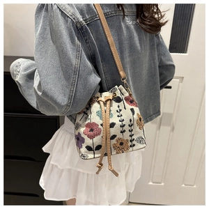 Detailed shot of ethnic floral embroidered bucket bag with beige PU leather strap