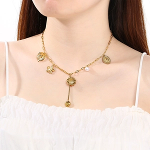Close-up of layered gold necklace featuring leaf, sun, heart charms and a white pearl
