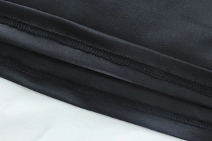 Detailed macro view of double-stitched hem on black mesh splicing fitted dress