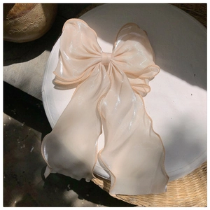 Detail of elegant beige organza bow hair clip with pearlescent ribbons and layers