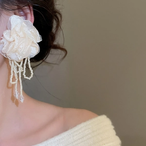 Close-up of elegant chiffon flower earrings with long beaded tassels on model