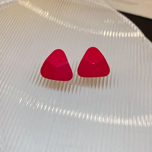 Gros plan détaillé de boucles d'oreilles triangulaires rouge rose mat sur plateau
