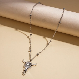 Detailed view of silver cow skull pendant with engraved texture on a beaded chain