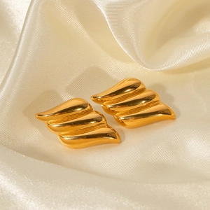 Detailed macro view of 18k gold vintage winged earrings on smooth champagne satin fabric