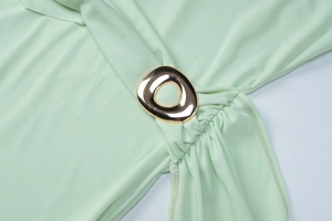 Détail de robe vert menthe avec anneau métallique doré et texture de tissu plissé élégant