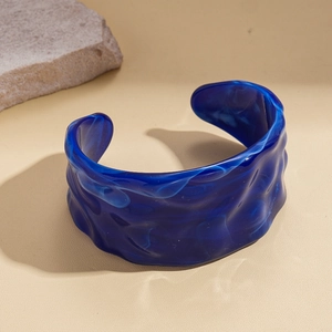 Detail of blue acrylic cuff bracelet with white marble swirls and wavy textured surface