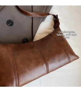 Detailed close-up of dark brown vintage PU leather texture and triple vertical stitching