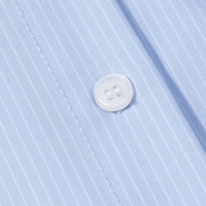 Close-up of a white resin button on a light blue pinstripe shirt fabric
