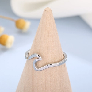 Polished silver wave ring on a wooden cone display against a blue background