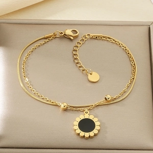 Détail du bracelet doré double couche avec pendentif tournesol et chaîne serpent fine